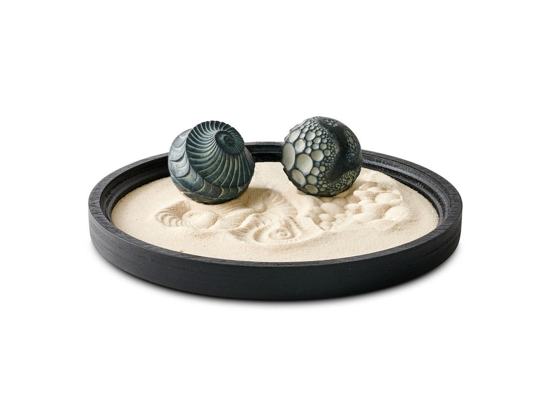 Black Lowtide Wonderscape with two patterned concrete Sand Spheres resting in fine sand.