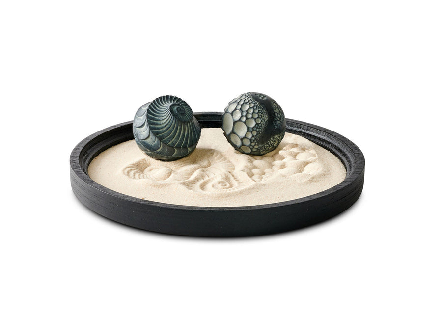 Black Lowtide Wonderscape with two patterned concrete Sand Spheres resting in fine sand.