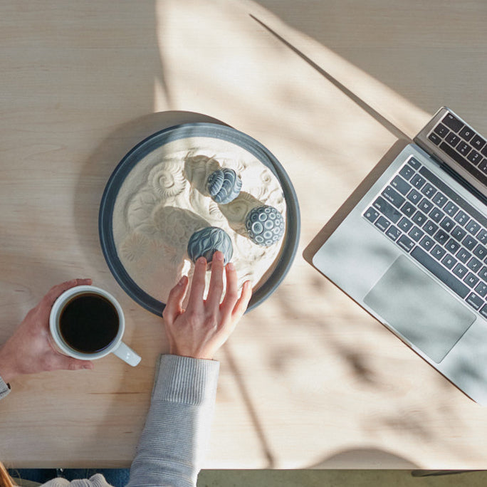 Employee practicing self-care at work with an Olander desk sand garden