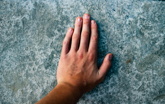 Hand resting on a textured stone surface for tactile grounding.