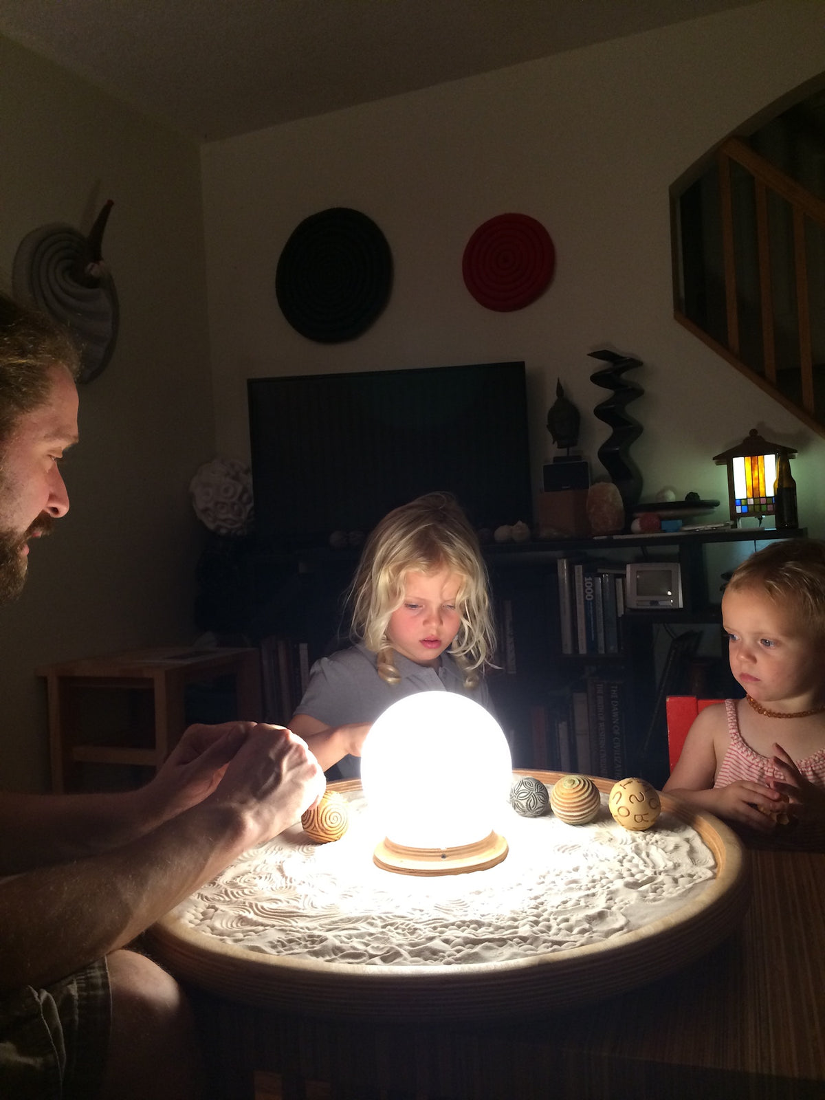Two children trying Olander Sand Sphere designs around a lit sand tray