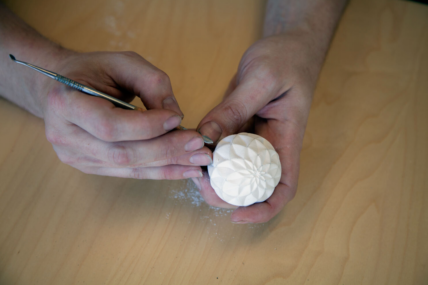 Hands carving an original Olander Sand Sphere pattern by hand