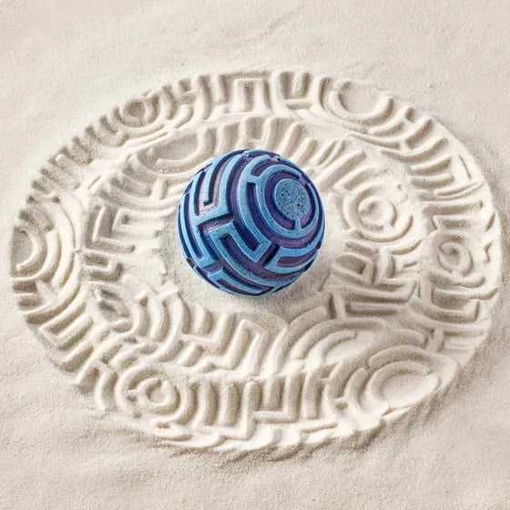 A blue Maze Sand Sphere on sand printed with its maze pattern.