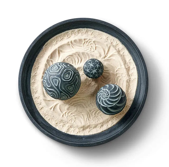 Adrift Wonderscape from above: a black tray of patterned sand with three dark blue textured Sand Spheres.